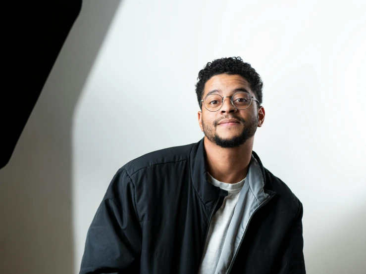 a man poses for the camera in front of a backdrop