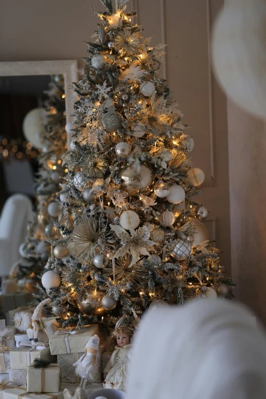 a christmas tree and presents by a large mirror