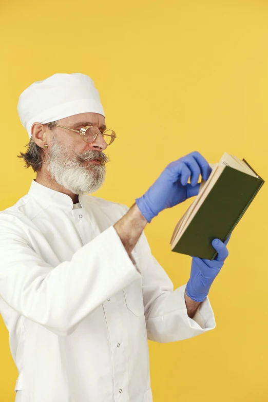 a chef dressed in white holds onto a book with gloves on