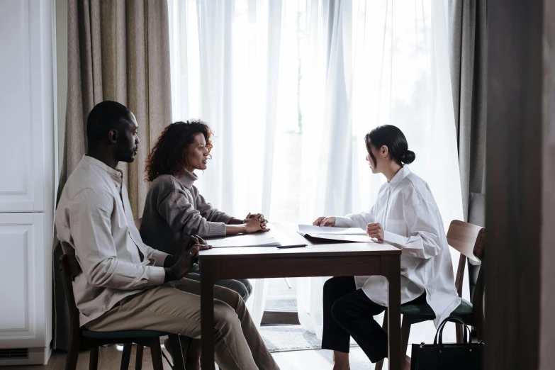 three people sit at a table and talk