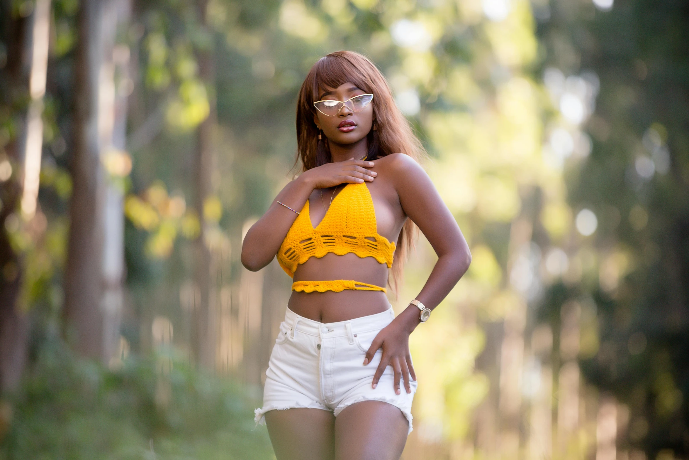 a woman in yellow top and shorts walking through forest