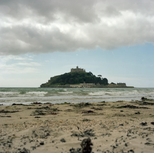 an island and waves with a small building on the island