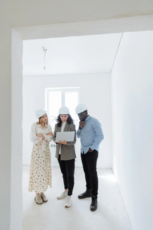 three people standing next to each other in a white room