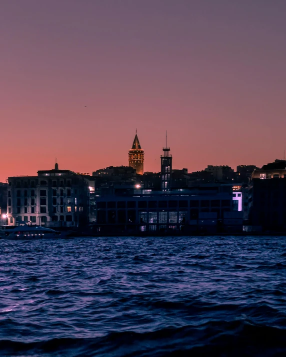 an old city skyline overlooking the water at sunset