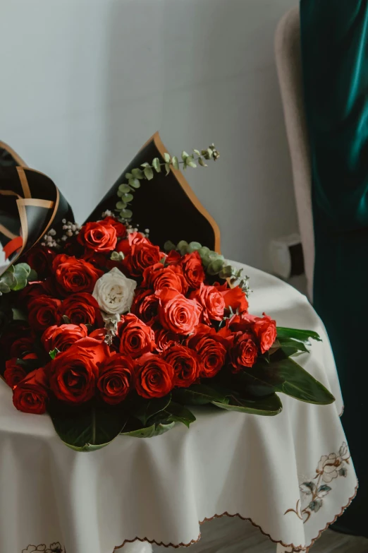 two rose bouquets sitting on top of a white tablecloth