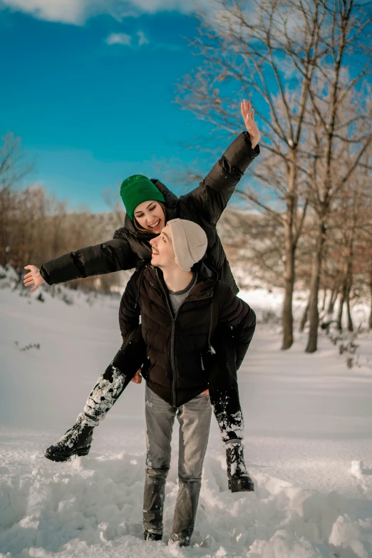 two people are smiling, they both are standing on the snow