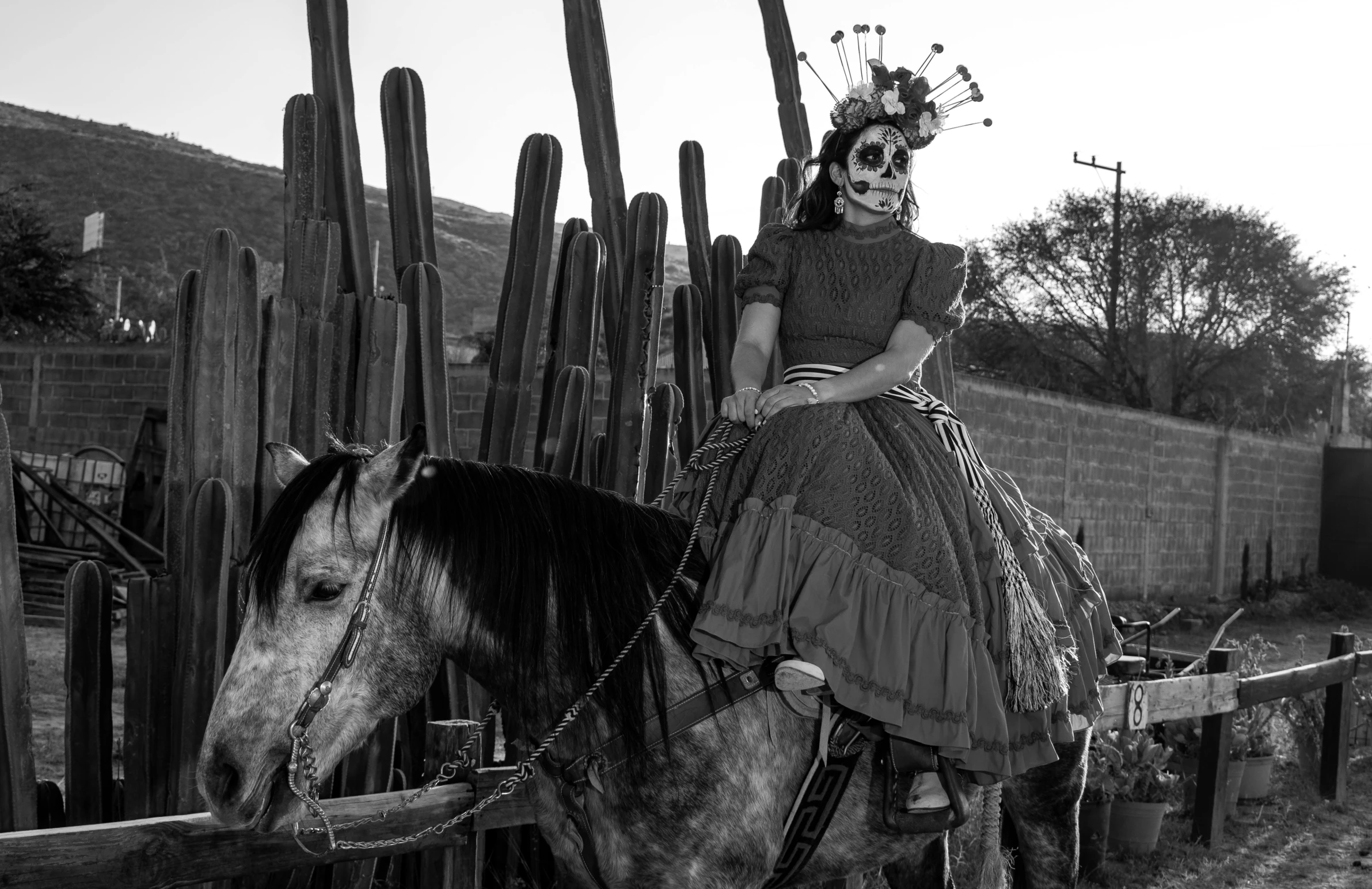 a woman in day of the dead makeup sitting on top of a horse