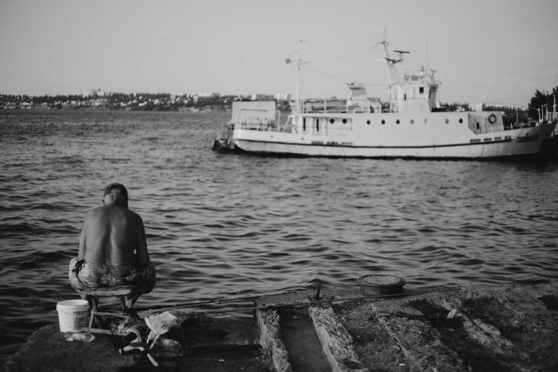 the person is sitting near the large boat