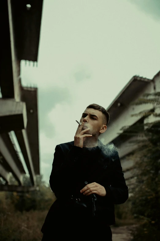 a man smoking a cigarette near some tall buildings