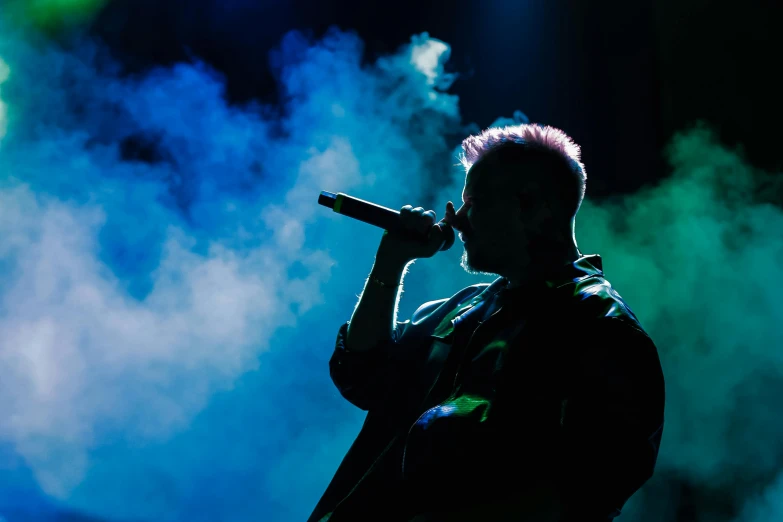 a man holding a microphone while singing on stage