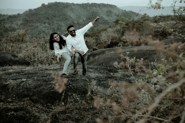 a couple standing together in a field with their arms around each other