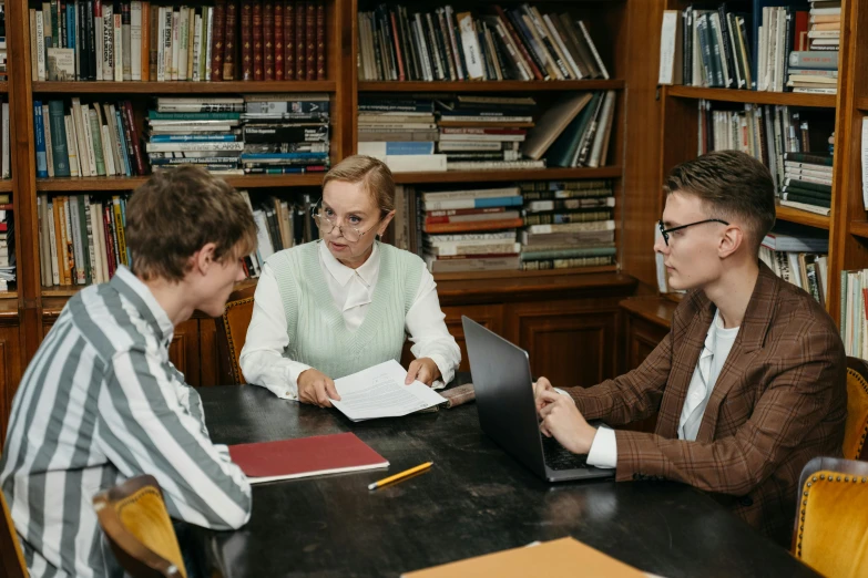 three people sitting at a desk in a liry