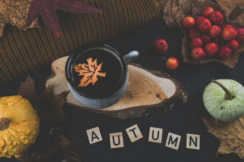 a cup of coffee sitting on top of an autumn leaf