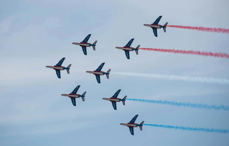 nine airplanes fly in the air trailing smoke