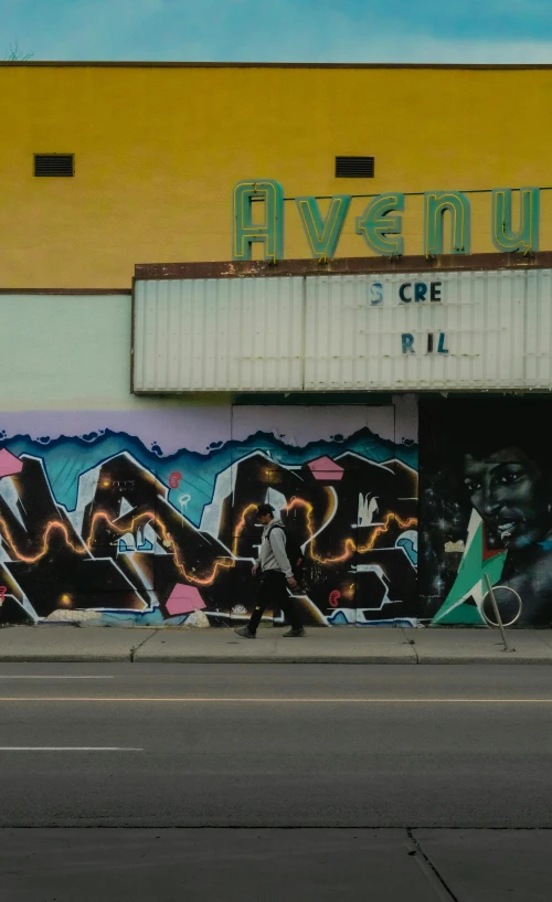 two people are walking down the street by a theater