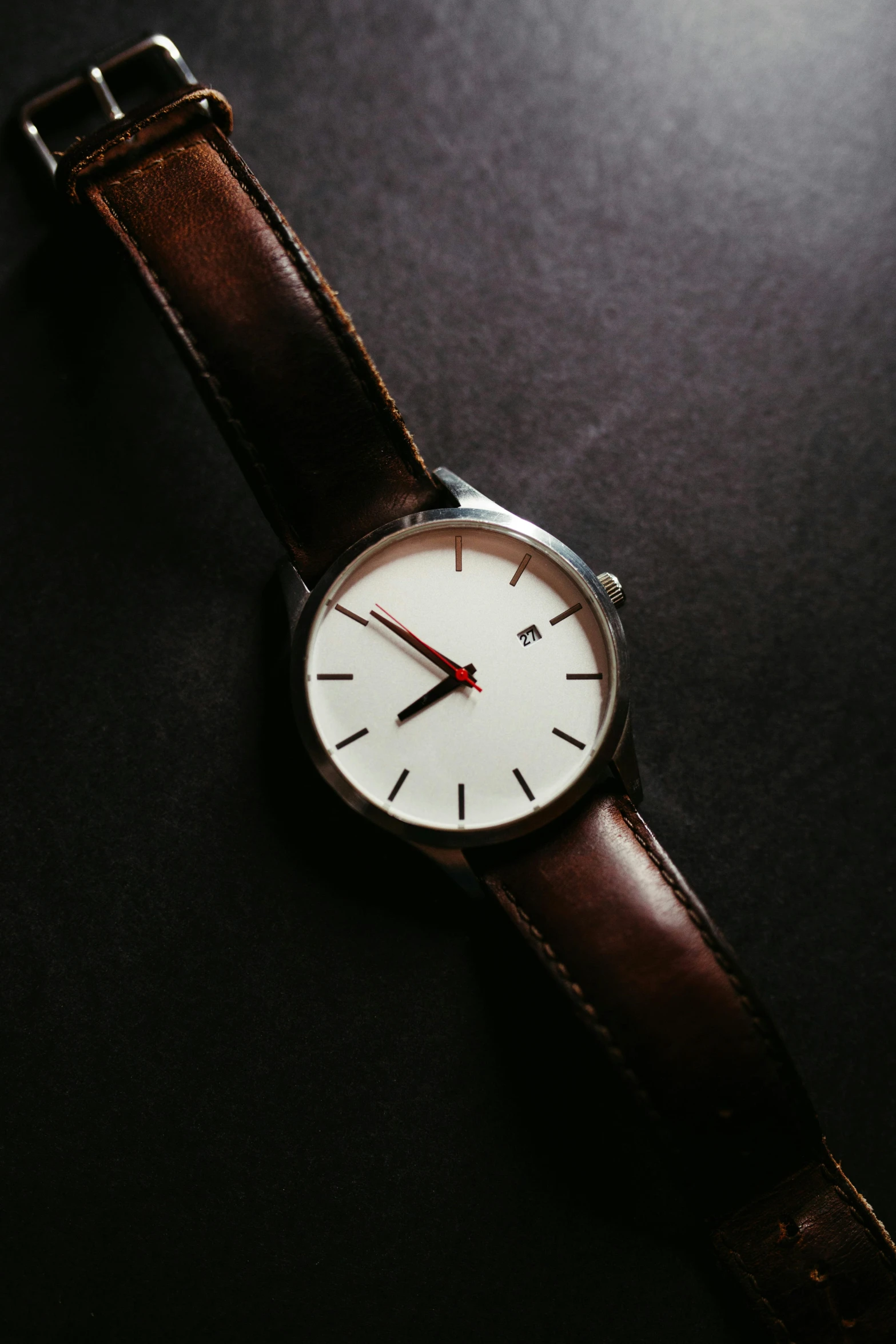 a watch is displayed on a dark surface