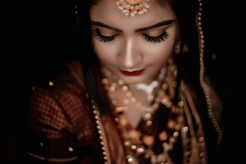 a woman wearing a headpiece looks down while holding her jewelry