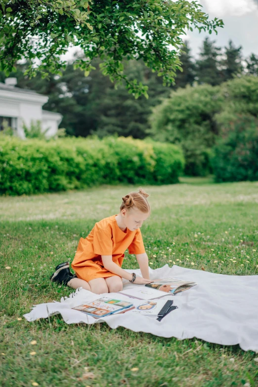 a child sitting on a blanket in the grass, drawing with crayons