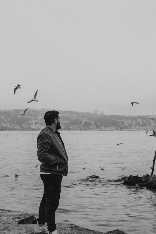 two men are looking at a body of water while birds are flying over them