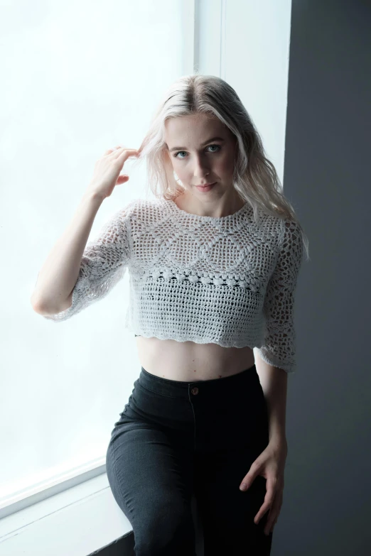 a girl is posing near the window in her shirt