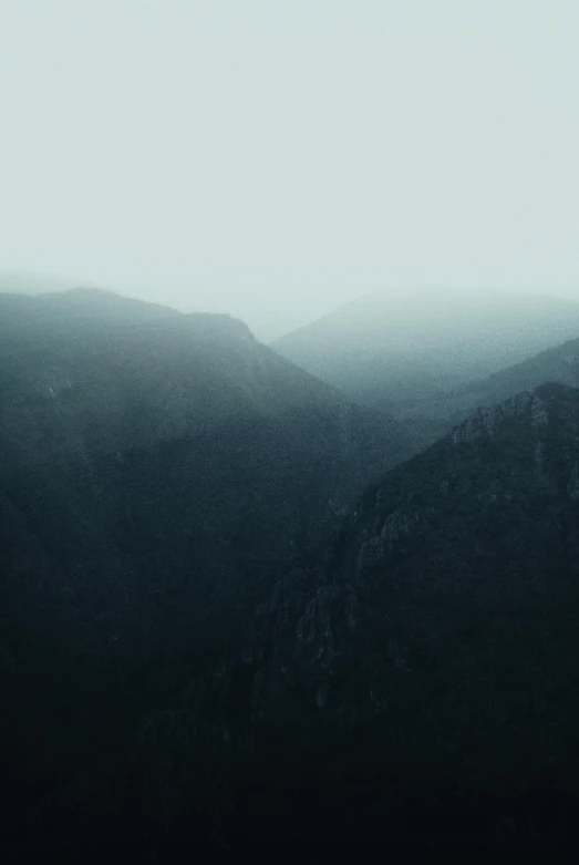 a dark mountain with hazy skies in the background