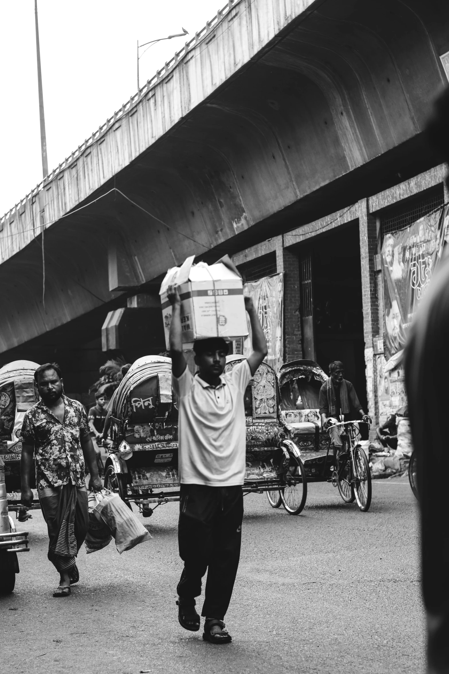 a man walks through the street carrying things on his head