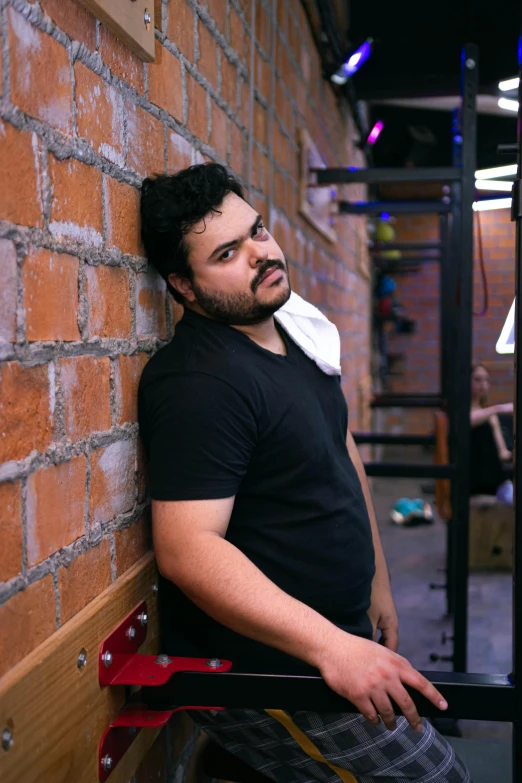 a man leaning up against a wall with a toothbrush in his mouth