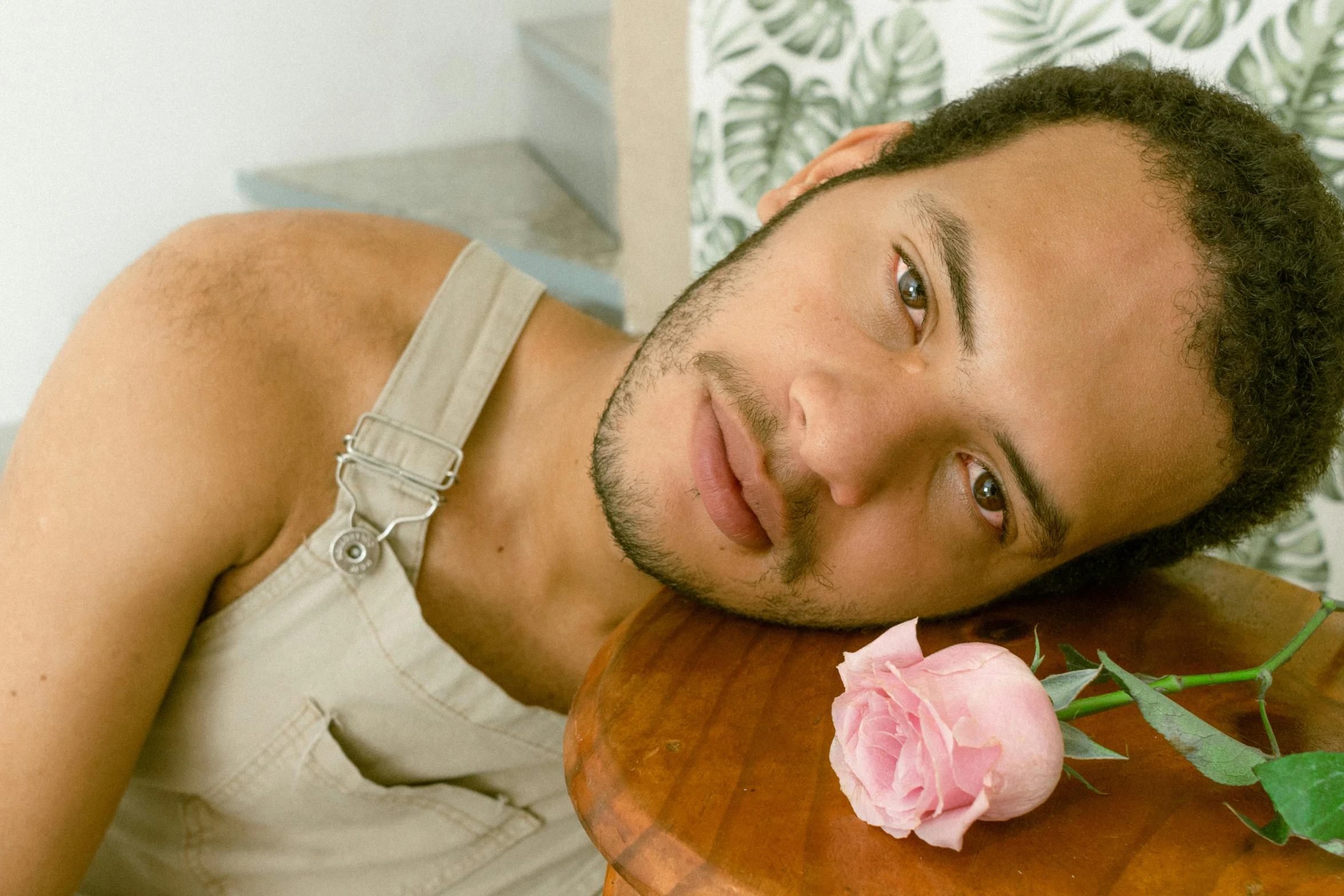 a young man is sitting down with a pink rose in front of him