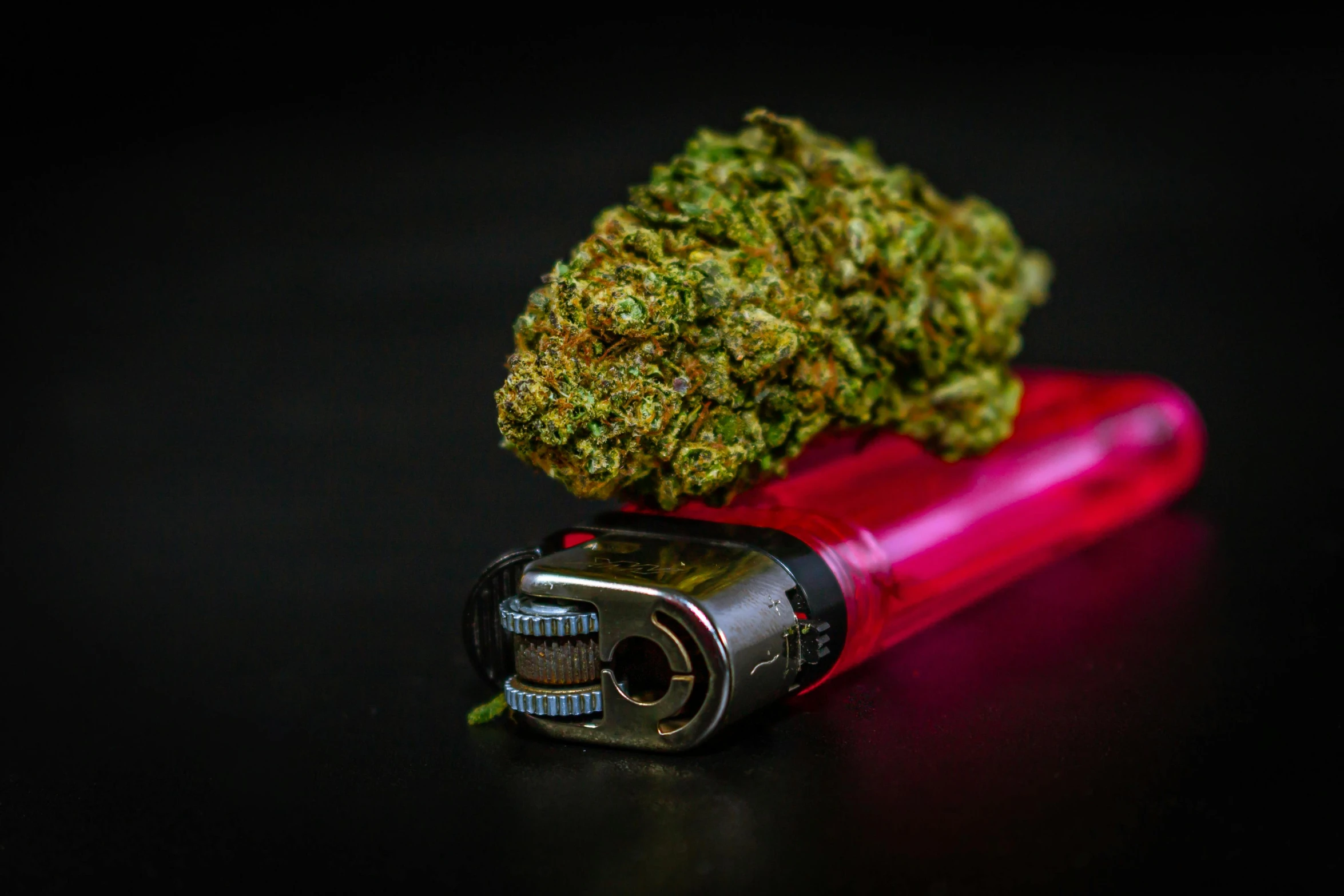 a cannabis flower on top of a red lighter