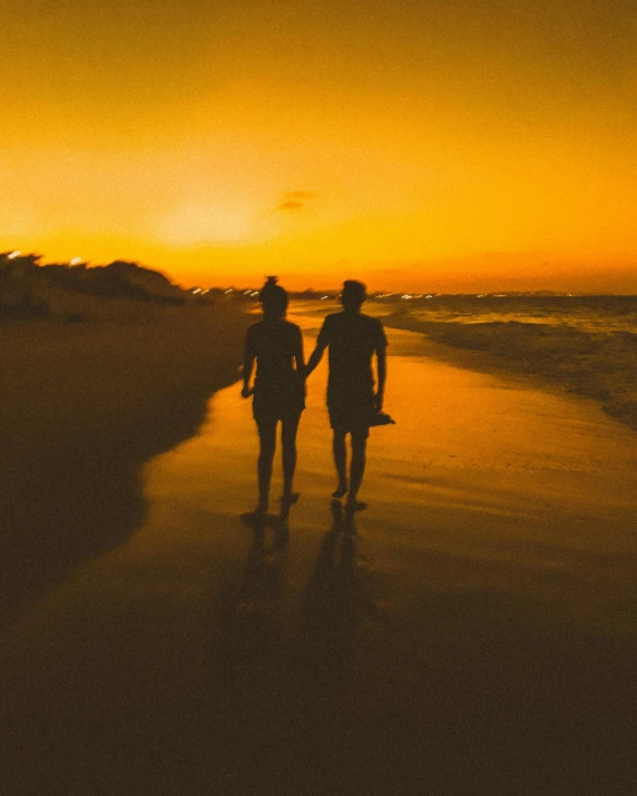 two people holding hands as they walk down the beach