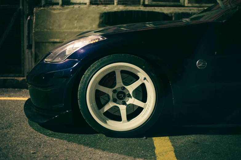 a blue car with white spokes parked near a sidewalk