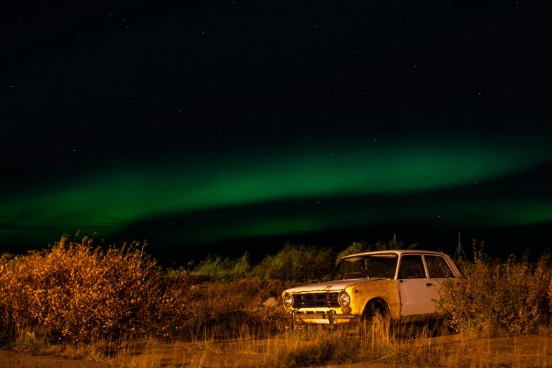 an abandoned car is parked in a field