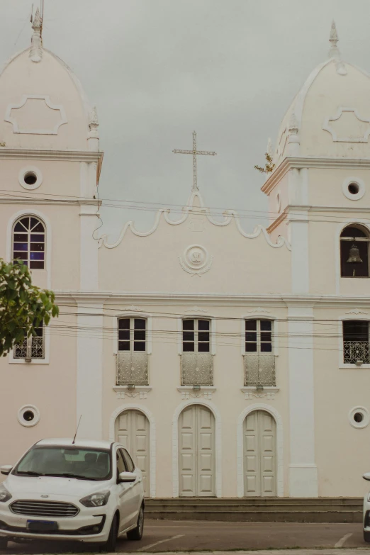 an old white church and parked cars outside of it