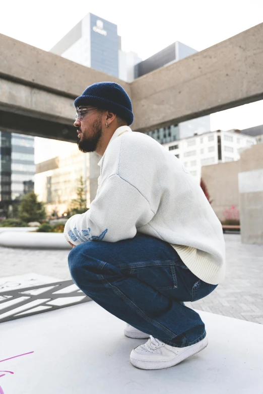 a man squatting down and leaning against a wall