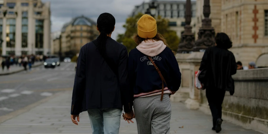 the two people are walking down the street holding hands