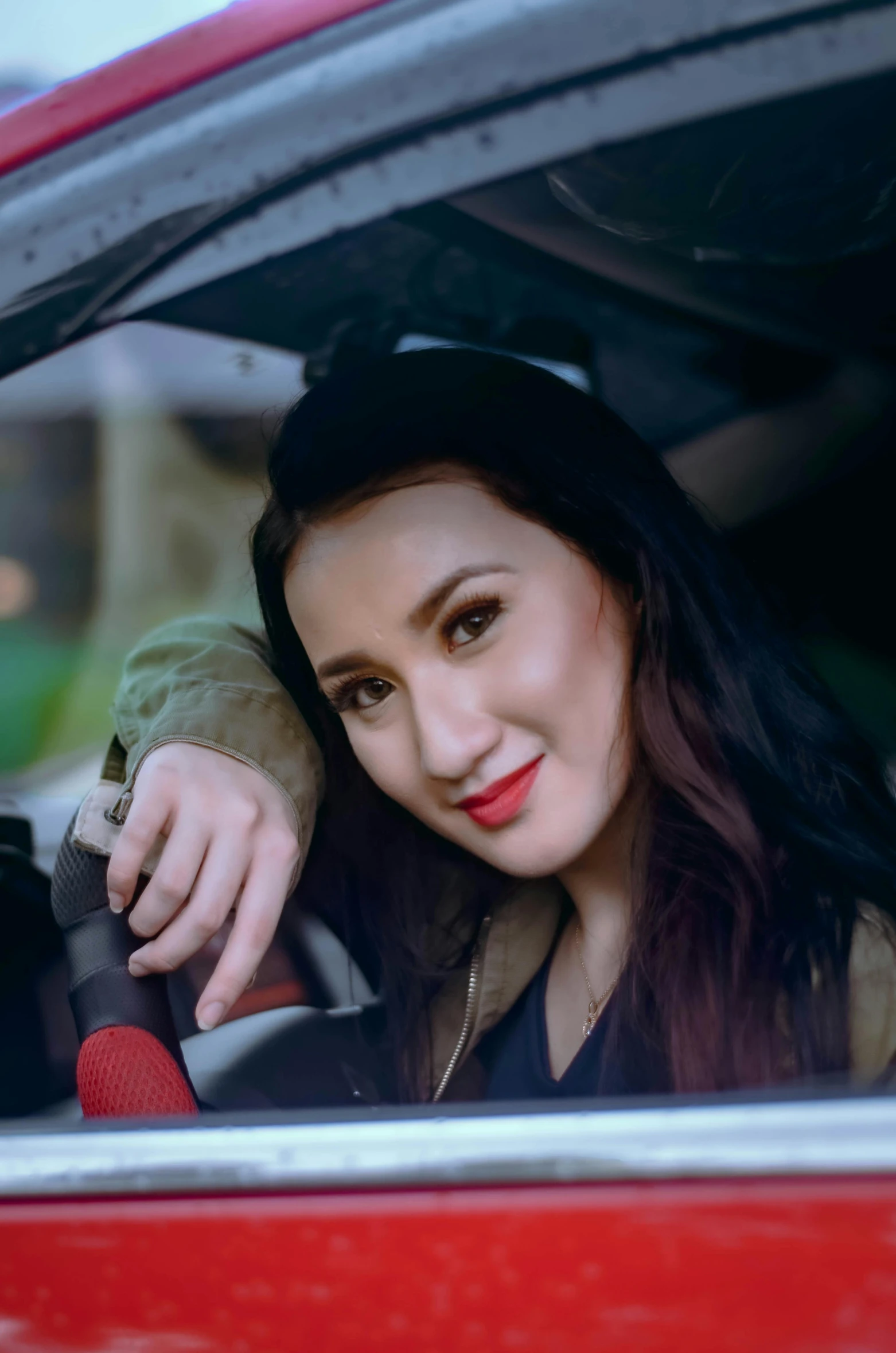 a woman with long black hair sitting in a car