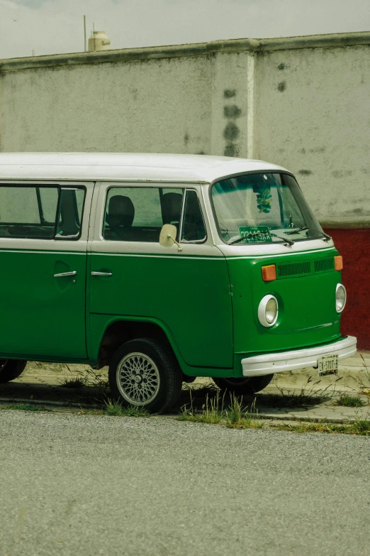 a small green bus is parked near an old building