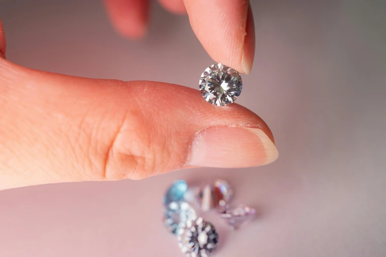 someone's hand holding two diamonds that look like they are on the ground