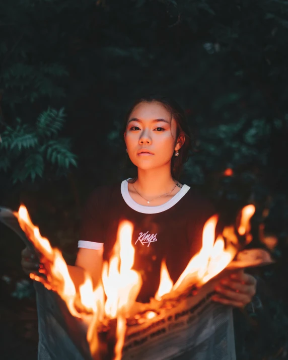 the young woman holds out a lit fire