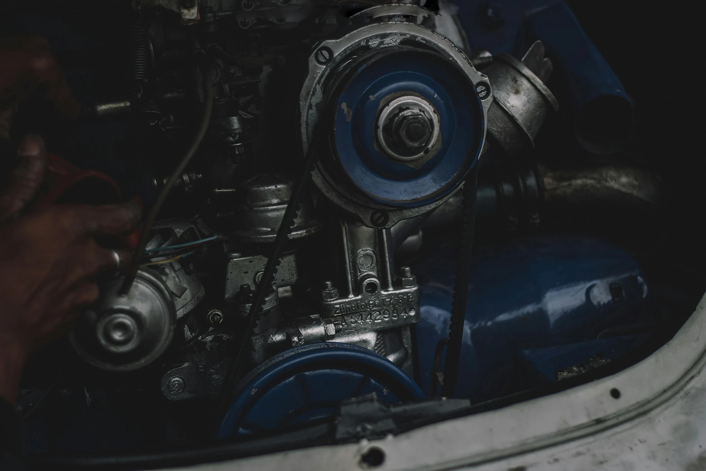 a person inspecting an engine with a man's hand