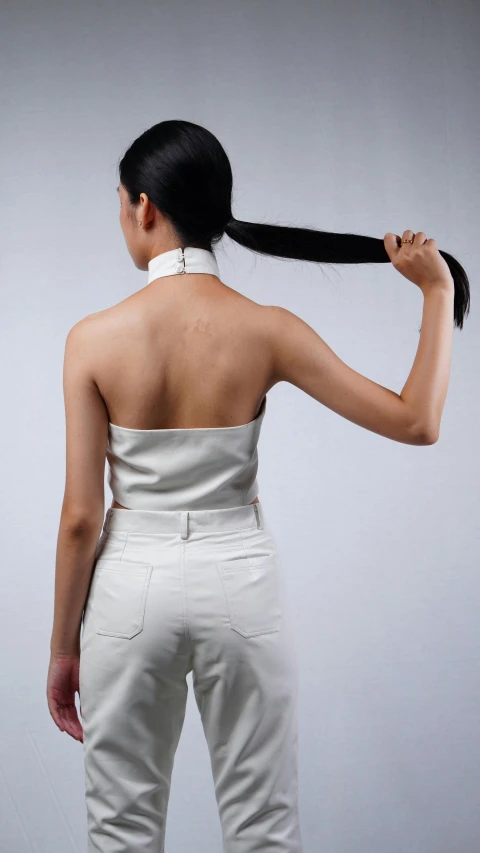 a woman with black hair standing in a white outfit