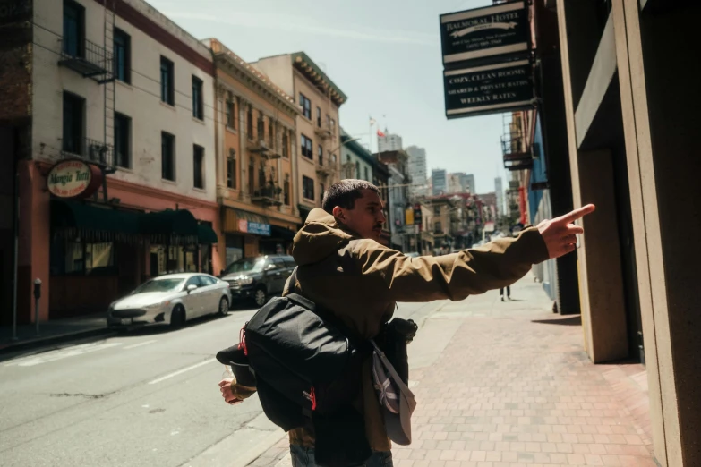 a man points at soing in a distance on a city street