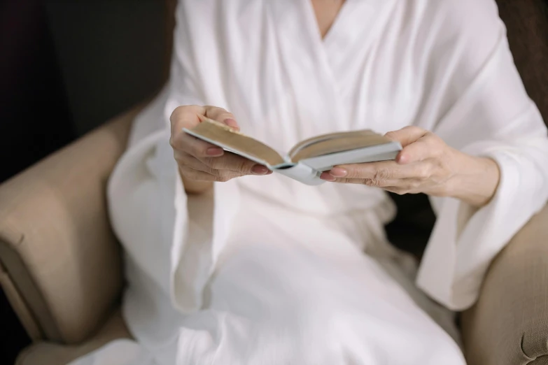 a woman in white dress holding open a book