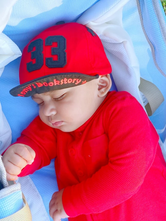 a young baby sleeping on a blue mat wearing a red hat