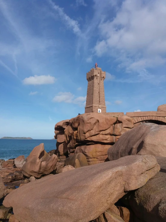 a lighthouse sitting atop rocks at the shore