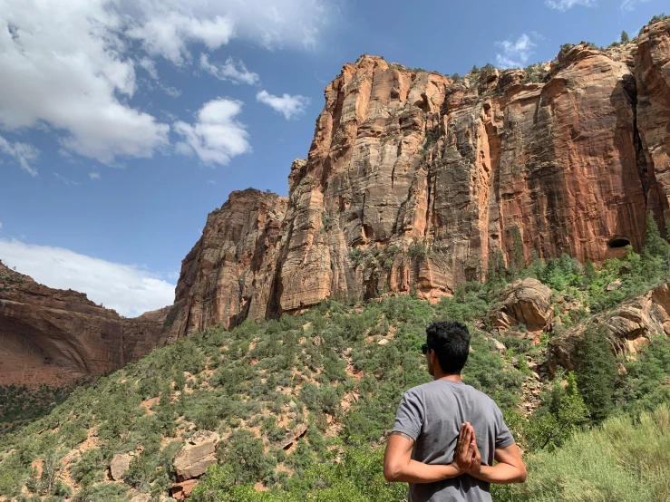 a man standing on a hill with a view of a cliff behind him