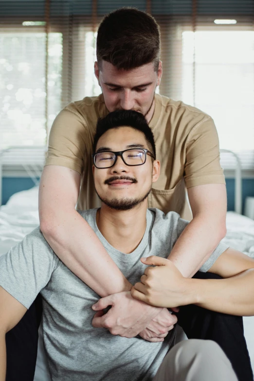 two men, one with glasses and one with arms around the other