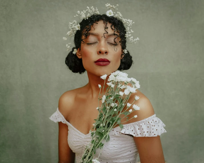 a woman dressed in a white dress holds a bunch of flowers