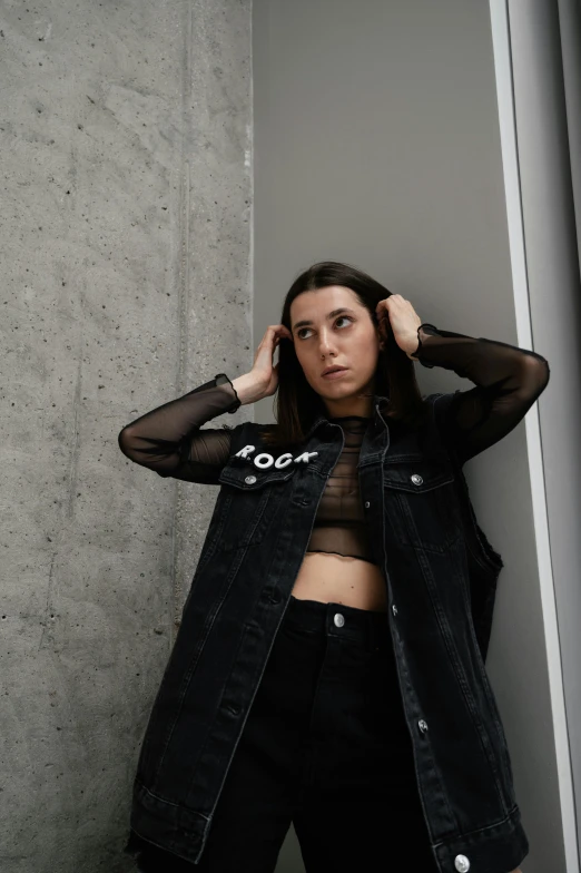 a woman posing in front of a wall with her hands on her head