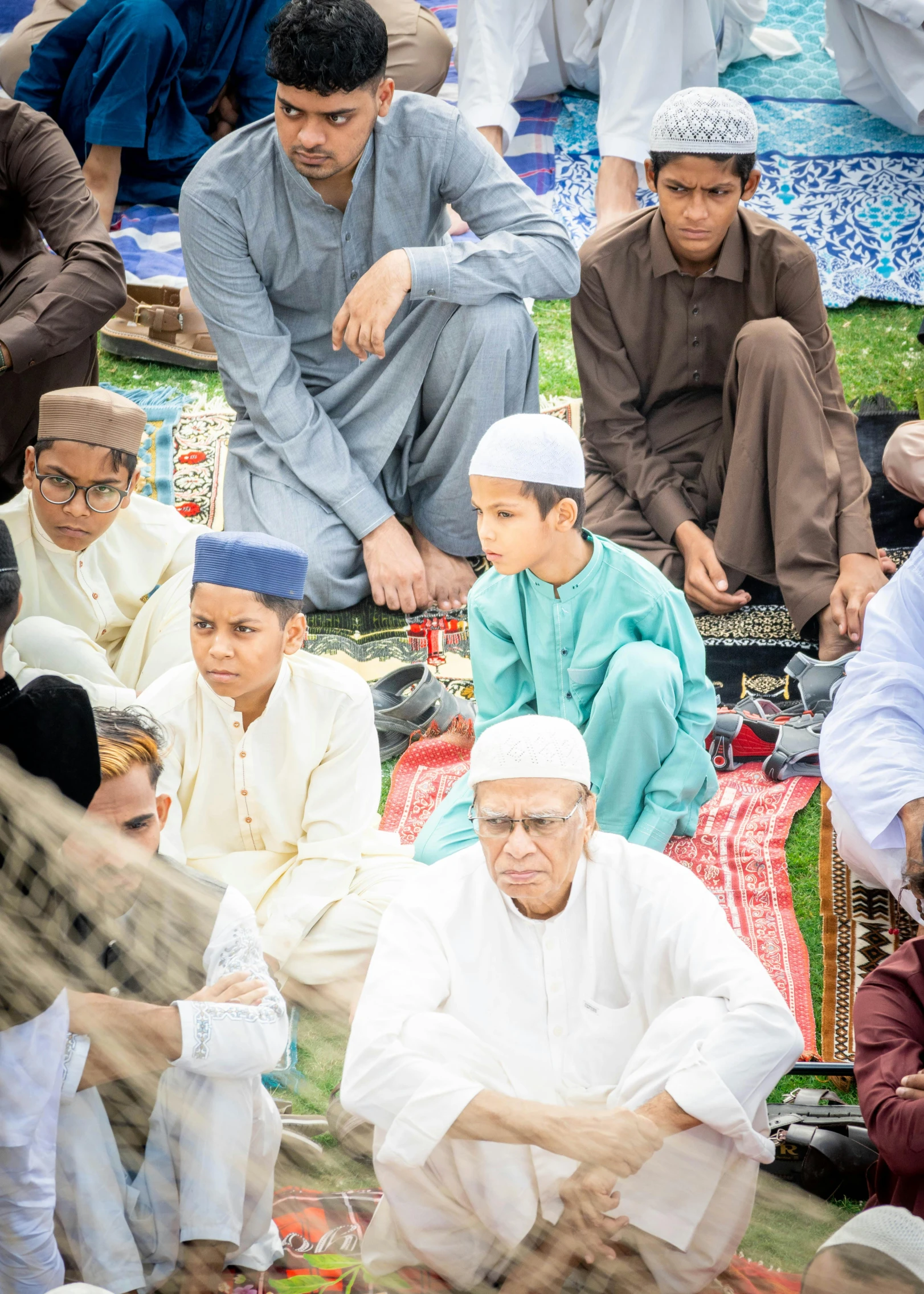 group of men sitting around a big rug together